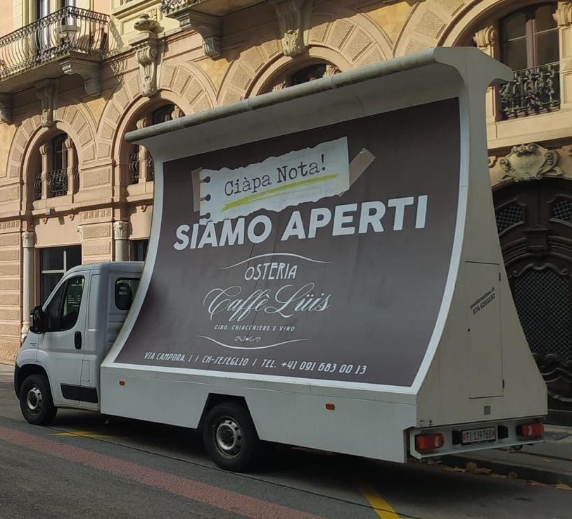 Camion vela pubblicitario in movimento su una strada urbana svizzera